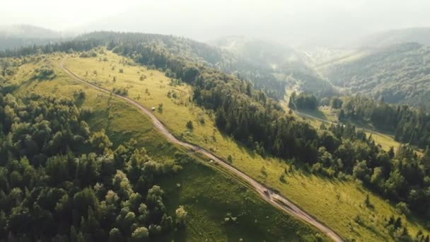 Antenni ammunta lentävät drone nuoren parin turisteja nauttii kauniita vuoria maisema auringonlaskun hidastettuna, kun ratsastaa mönkijä kuljetus. Pariskunta ajaa mönkijällä. — kuvapankkivideo