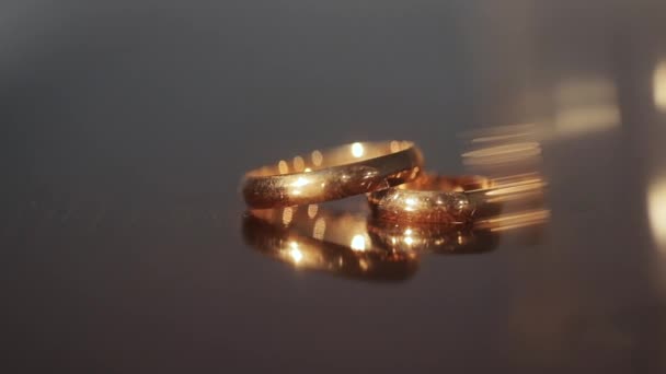 Two wedding rings at the table. Gold engagement rings on beige background. Wedding Rings. Two splendid wedding rings on a wedding day — Stock Video