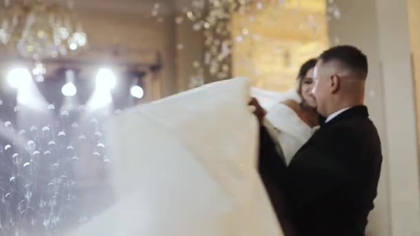 Confetti in aria. Bella bruna sposa e bello sposo ballare il primo ballo alla festa di nozze . — Video Stock