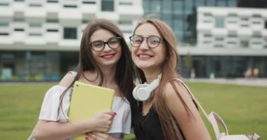 İki mutlu kafkas genç kadın en iyi arkadaş moda güneş gözlüğü giyen eğlenmek, açık poz, kamera bakarak