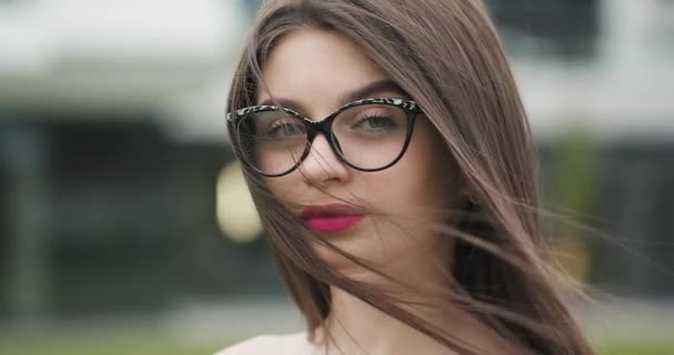 Крупним планом обличчя чарівної позитивної молодої європейської жінки в окулярах дивлячись на камеру — стокове відео