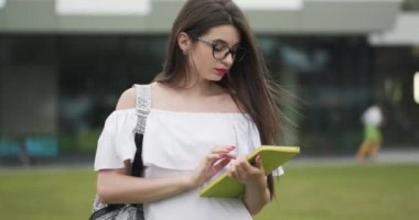 Portre genç güzel iş kadını tablet cihazı kullanarak açık havada büyük kentsel bina ayakta iken