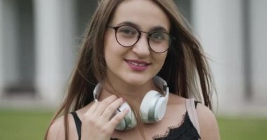 Genç kadın kentsel sokak arka planda gülümsüyor. Mutlu kızın şehir caddesinde gülümseyen portresi. Moda modeli gülümseme yakın. Güneş gözlüğü mutlu kadın kameraya bakıyor