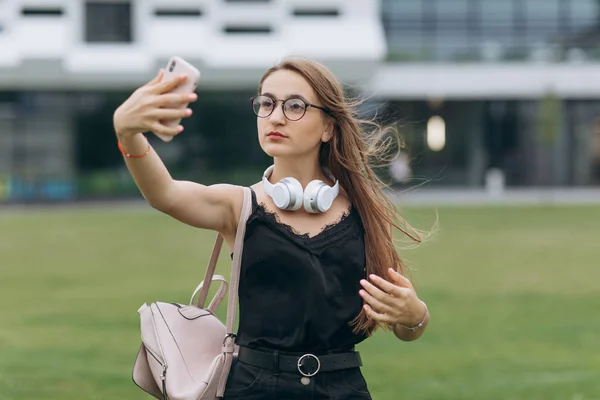 Portret szczęśliwy wesoły uśmiechnięty młody uczeń uczennica Pani z długimi włosami noszenia okularów patrząc aparat zrobić selfie. — Zdjęcie stockowe