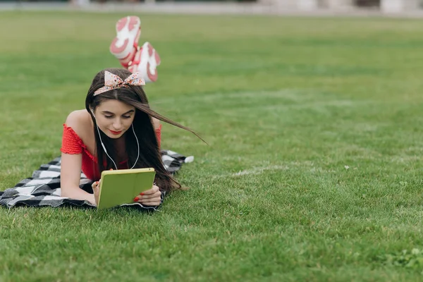 Młoda kobieta słucha muzyki. Młoda kobieta z słuchawkami i smartfonem słuchając muzyki na trawie — Zdjęcie stockowe