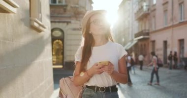 Şehir caddesinde yürüyen ve akıllı telefonuna bakan genç kadın