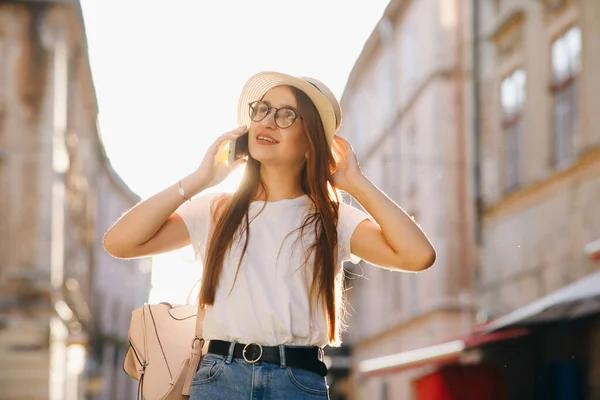 Γυναίκα με καπέλο και γυαλιά στέκεται στην οδό Σίτι, μιλώντας στο κινητό, χαμογελώντας, γελώντας. Hipster κορίτσι περπατά. Ηλιόλουστη μέρα. — Φωτογραφία Αρχείου