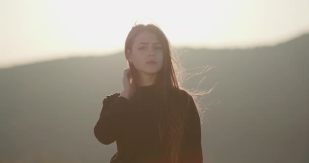 Mujer morena joven retrato mira a la cámara. Primer plano retrato de una hermosa mujer disfrutando de un atardecer tranquilo explorando la espiritualidad mirando hacia arriba orando contemplando el viaje con el viento soplando pelo . — Vídeos de Stock