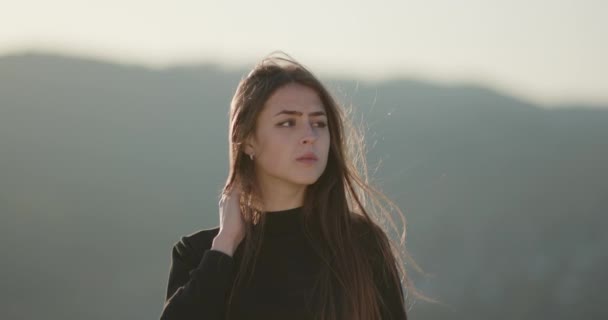 Utomhus Porträtt av ung kaukasisk tonåring flicka ler och tittar in i kameran på en blåsig dag — Stockvideo
