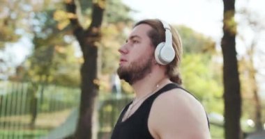 Yakışıklı genç bir sporcunun portresi, elinde telefon, spor kıyafetleri içinde, dışarıda koşuyor. Kavram: Aşk sporu, sağlıklı yaşam tarzı, güzel, kaslı, mutlu, yanık kalori.