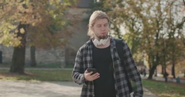 Yaz parkında şişeden su içen susamış bir adam. Spor yapan adamın açık hava antrenmanından sonra su içtiği portre. Spor fitness erkek modeli antrenman uygulaması kullanıyor.