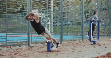 Park yerinde çift egzersizi. Mükemmel kalçalar için antrenman. Spor kıyafetli genç kadın ve erkek sporcu. Yeşil parkta antrenörle fiziksel egzersiz yapıyorlar..