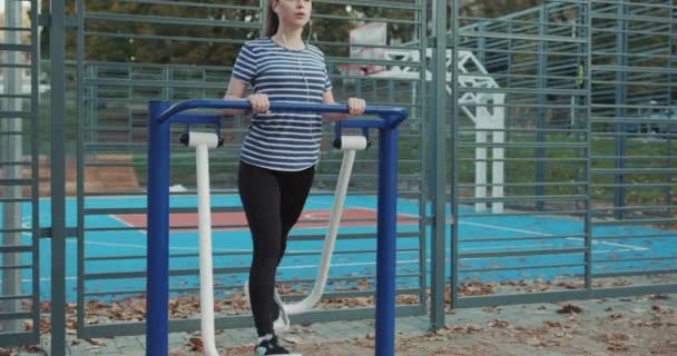 Exercising on outdoor gym equipment. Woman working out at gym machine. Autumn time outdoors activities. — Stock Video