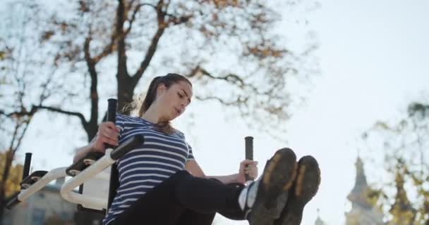 Exercising outdoors in the morning in autumn park. Strong young girl is doing press dips Concept of motivation and sports nutrition. Workout. Girl Outside on Nature — Stock Video