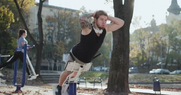 Athletische junge Frauen und Männer in Sportbekleidung, die mit Trainer im grünen Park im Freien körperliche Übungen machen. Training für perfekte Hüften. Paar übt im Park. — Stockvideo