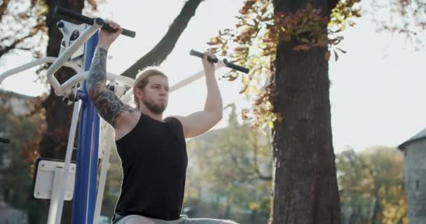 Atleta di sesso maschile che si allena all'aperto. Giovane ragazzo muscoloso che allena le braccia per essere forte. Allenamento del ragazzo in forma nel parco. Fitness e stile di vita sportivo concetto. Giovane uomo spingendo all'aperto — Video Stock