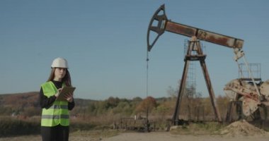 Kasklı kadın mühendis tablet bilgisayar kullanıyor. Endüstri Petrol Mühendisi Kadın Dijital Tablet Petrol Pompası Alanı üzerinde çalışıyor