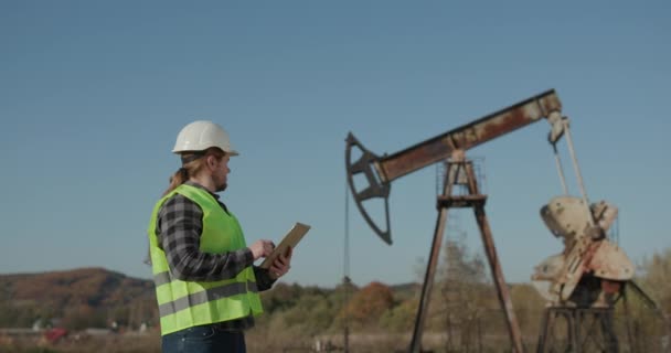 Energie-industrie Business Man Holding Apparaat met behulp van Digital Tablet Oil Pump Field. Pompjack Technicus Man Werken Digitale Tablet Checking Report Oil Pump Farm Job. — Stockvideo