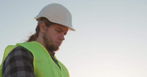 L'ingegnere del casco lavora in fabbrica con un tablet elettronico. Creazione di nuove tecnologie, sviluppo della produzione — Video Stock