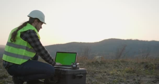 Lucrător în construcții, om caucazian care lucrează cu cască de siguranță și folosind laptop cu afișaj cheie cromatică — Videoclip de stoc