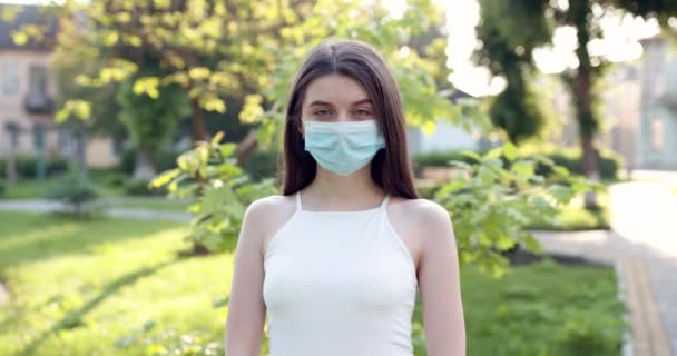 Gros plan portrait d'une brune caucasienne portant un masque médical protecteur sur son visage. L'épidémie du virus de la grippe et du coronavirus est partout . — Video