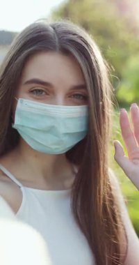 Maskeli kadın vlogger kameraya bakarak el sallıyor. Çevrimiçi olarak arkadaşlarıyla iletişim kuran kız video görüşmesi yapıyor. Konuşan yaşam tarzı vlog iş görüşmesi.