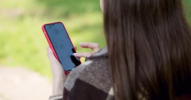 Parkta cep telefonu kullanan genç kızı kapat. İnternet, akıllı telefon, yakın çekim model, instagram, facebook konsepti