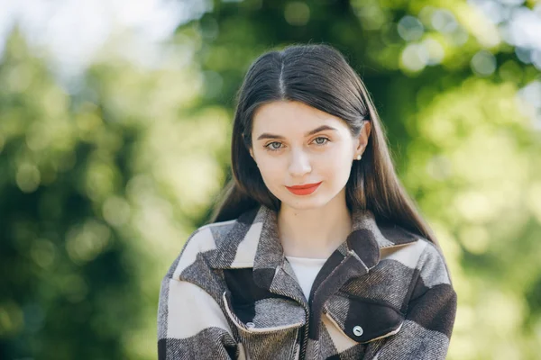 Ritratto di bella ragazza con i capelli lunghi su sfondo alberi. Attraente giovane donna godendo il suo tempo all'aperto tra gli alberi con il tramonto sullo sfondo. Primo piano volto alla ricerca di fotocamera — Foto Stock