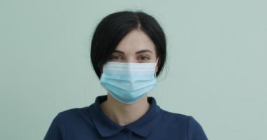 Sağlık Koruma Corona Virüsü Konsepti. Tıbbi maskeli genç bir kadın. Kadın derin derin nefes alır ve kameraya bakar..