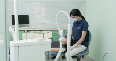 Diş beyazlatma prosedürü. Diş hekimi stomatolojisti diş hekimliği kliniğinde dişlerini lambayla beyazlatıyor. Diş bakımı ve diş hekimliği kavramı