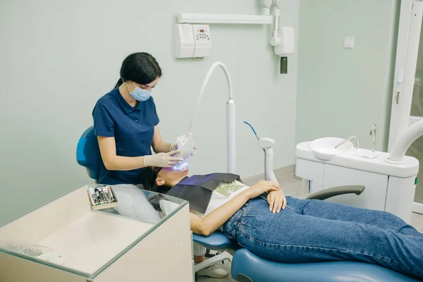 Dentista estomatologista clareamento dos dentes para o paciente na clínica odontológica medicina com lâmpada. Conceito de cuidados dentários e odontologia. Procedimento de clareamento dos dentes — Fotografia de Stock