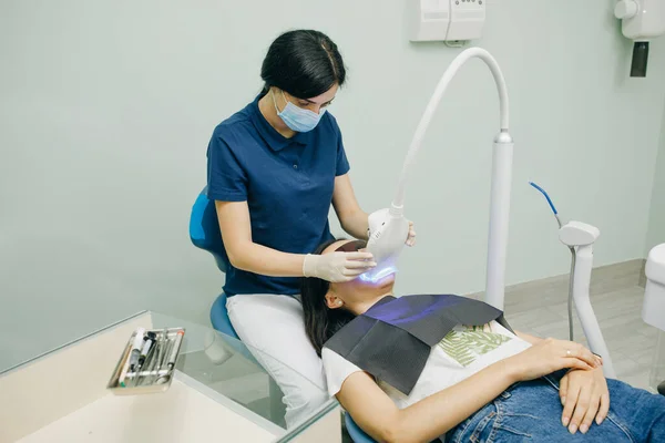 Procedimento de clareamento dos dentes. Dentista estomatologista clareamento dos dentes para o paciente na clínica odontológica medicina com lâmpada. Conceito de cuidados dentários e odontologia — Fotografia de Stock