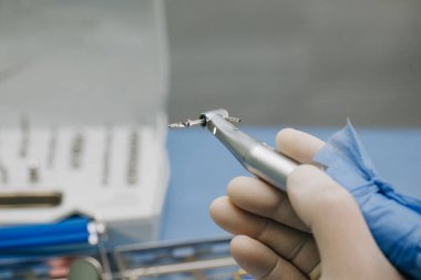 Diş hekimi, dişçi kliniğinde dişçi aletleri tutuyor.