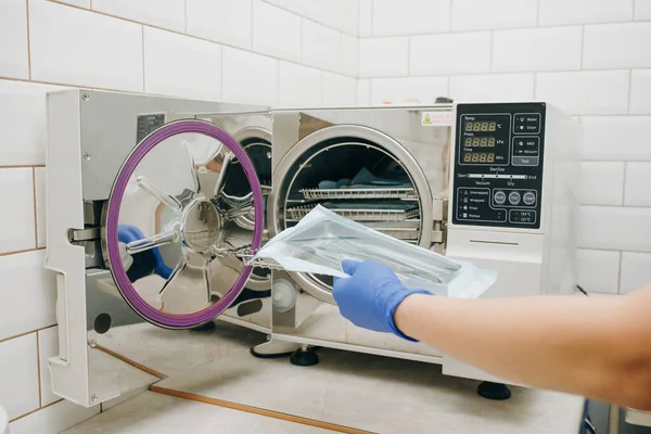 Assistent met steriel tandartsgereedschap. Steriliseren van medische instrumenten in autoclaaf. Tandartspraktijk — Stockfoto