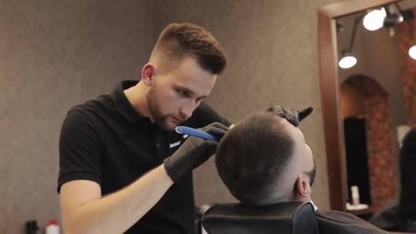Coupe barbe avec lame à l'ancienne au salon de coiffure. Style barbe. Barbier professionnel rasage barbe client avec rasoir droit en gants noirs. — Video