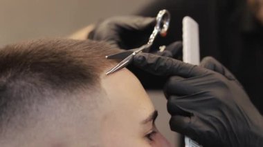 Berber müşteriyi berber dükkanında makasla keser. Kuaför saç kesiyor.