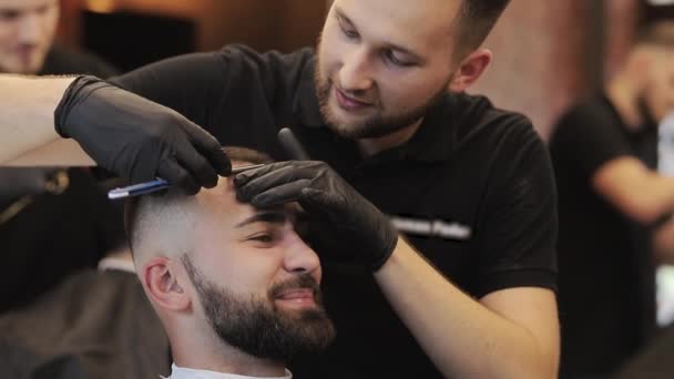 Der Meister gibt die Kontur des Haarschnitts vor. Herrenfrisur in einem Friseursalon. Professionelle Friseure rasieren Kunden mit Rasiermesser. Master Cut mit altmodischer Klinge beim Friseur — Stockvideo