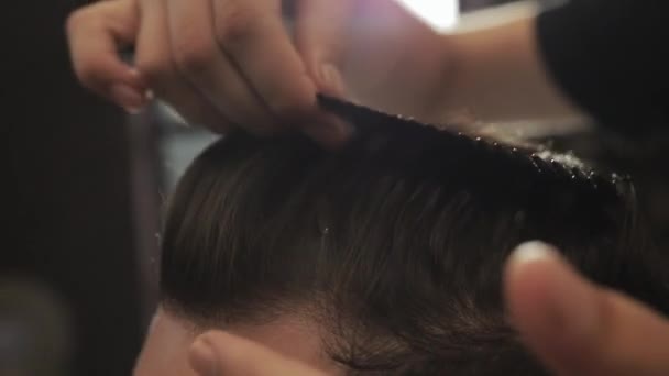 Siyah eldivenli siyah saçlı berber berber berber dükkanında müşterisinin saçını kesiyor. Profesyonel ve düzgün saç bakımı. Saç ve sakal kesiyorum. Kuaför erkek kuaföründe kuaförlük yapıyor.. — Stok video