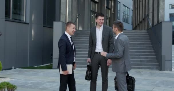 Felices colegas hablando de pie fuera del centro de negocios, personal sonriente personas profesionales riendo disfrutar de una conversación amistosa en el espacio de trabajo — Vídeos de Stock