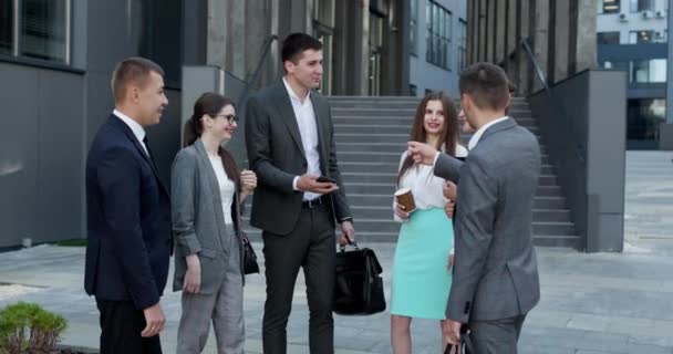 Homens e mulheres empresários discutem negócios. Grupo de seis jovens empresários caucasianos, homens e mulheres que se reúnem para discutir fora do edifício de escritórios — Vídeo de Stock