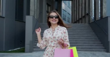 Başarılı bir alışveriş yaptıktan sonra alışveriş merkezinden ellerinde poşetlerle çıkan bir grup mutlu genç kız. Güneşli Gün.