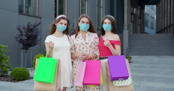 Группа молодых красивых женщин в масках, чтобы защитить коронавирус, стоящий перед торговым центром с сумками в руках. — стоковое видео