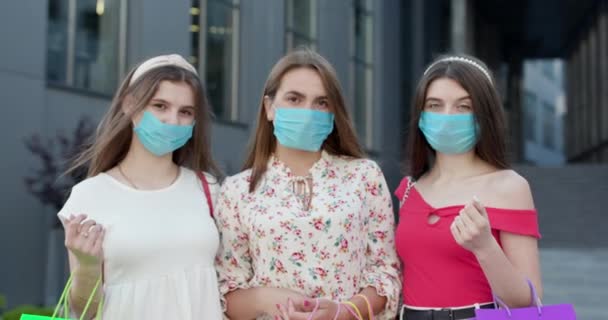 Группа молодых красивых женщин в масках, чтобы защитить коронавирус, стоящий перед зданием с сумками в руках. — стоковое видео