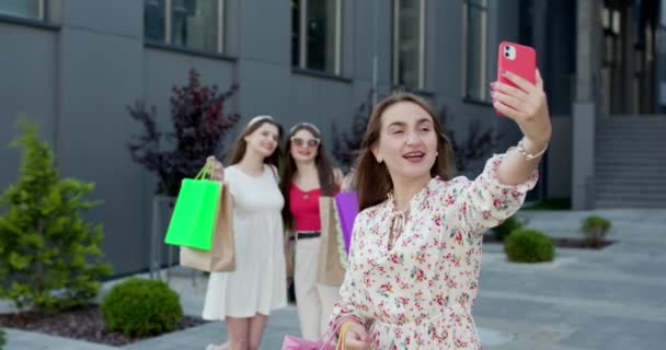 En grupp unga vackra kvinnor i avslappnade kläder gör selfie efter lyckad shoppingdag. suddig bakgrund. — Stockvideo
