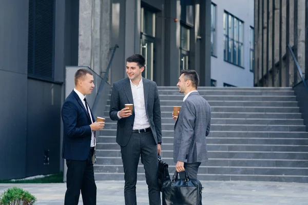 Group of entrepreneurs men in formal clothing are talking discussing business with drinks. People and communication concept