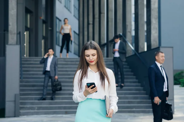 Kaukaska Pewna siebie młoda kobieta biznesu korzysta z aplikacji Smartphone na zewnątrz w pobliżu Modern Office Building — Zdjęcie stockowe