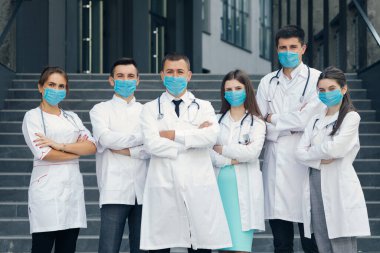 Yüz maskeli bir grup doktor kameraya bakıyor. Takım çalışması Uzmanı Doktorlar. Corona Virüsü ve Sağlık Hizmetleri Konsepti