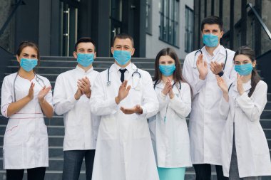 Coronavirus 'la mücadele eden hastane sağlık personeli, destekleri için halkı ve polis memurlarını alkışlıyor. Yüz maskeli bir grup doktor. Corona Virüsü ve Sağlık Hizmetleri Konsepti