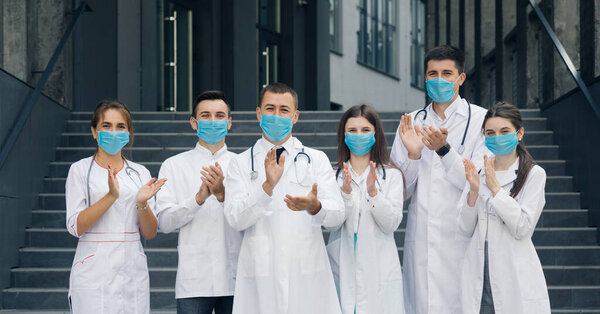 Corona Virus and Healthcare Concept. Medical staff from the hospital who are fighting coronavirus applaud back the people for their support. Group of doctors with face masks looking at camera.