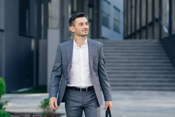 Modern businessman. Confident young man in suit looking away while standing outdoors with cityscape in the background. Handsome confident businessman portrait.